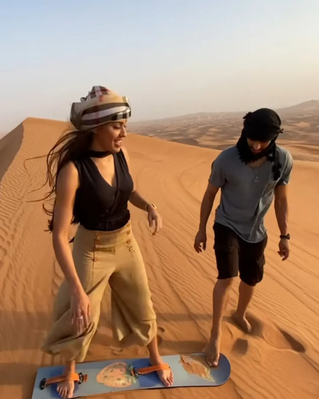 Traveller sandboarding down a dune in the Dubai desert
